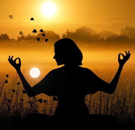 Woman meditating in a field with a gorgeous sunset